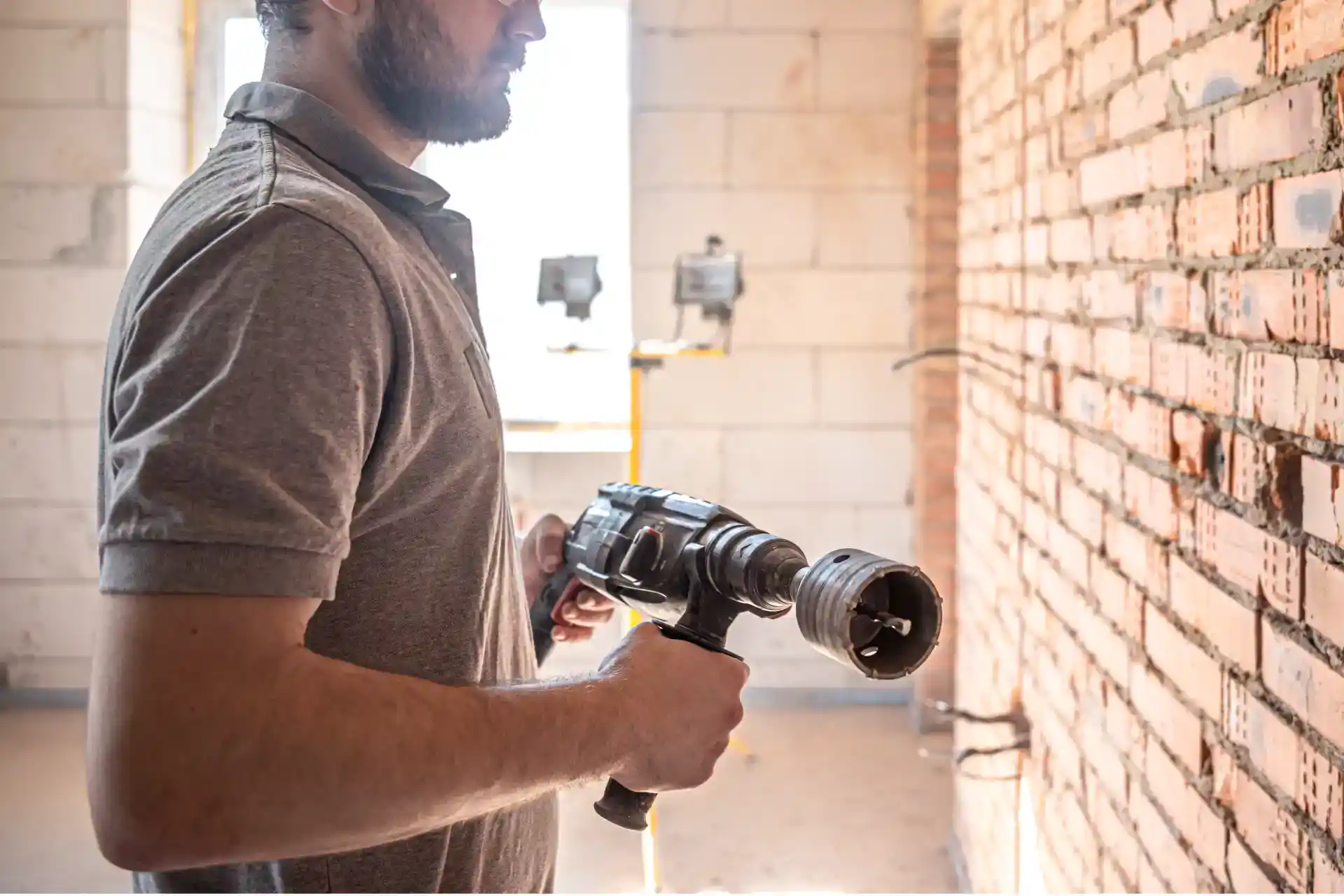 Brydning af mursten med elektrisk boremaskine til byggeri og renovering.
