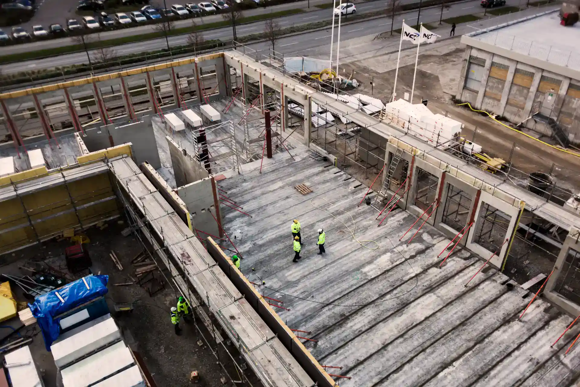 Konstruktion af nyt erhvervsbyggeri med byggemandsarbejde og sikkerhedsforanstaltninger.