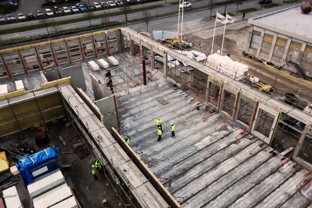 Betonarbejde på byggeplads med arbejdere i sikkerhedsudstyr.
